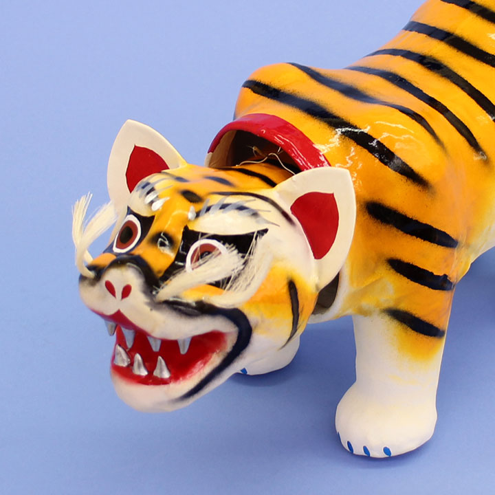 Un tigre en papier mâché décoré d'une poupée de mai, un petit tigre